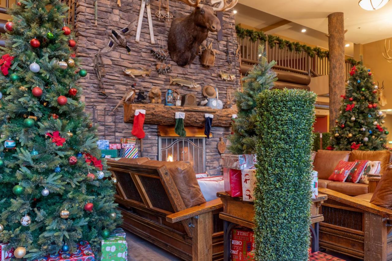 The Grand Hotel At The Grand Canyon Тусан Екстериор снимка The photo shows a cozy holiday scene with a rustic aesthetic. In the center, there is a wooden bench in front of a stone fireplace, which is adorned with festive decorations. Above the fireplace, a mounted moose head adds a touch of wilderness charm.