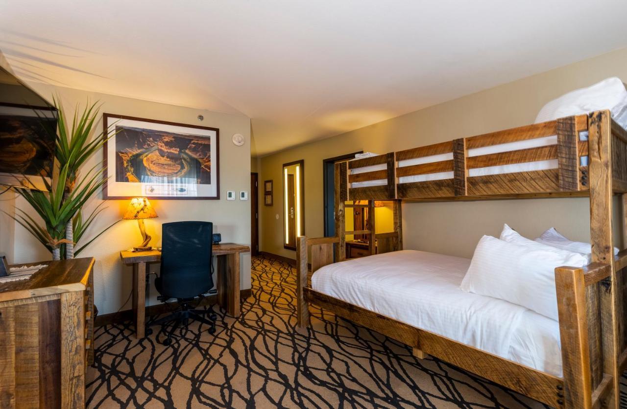 The Grand Hotel At The Grand Canyon Тусан Екстериор снимка The photo shows a cozy hotel room. It features a bed with white bedding and a wooden headboard. Beside the bed, there is a bunk bed structure, though it is currently not occupied. A desk with a chair is positioned against one wall, and there is a lar